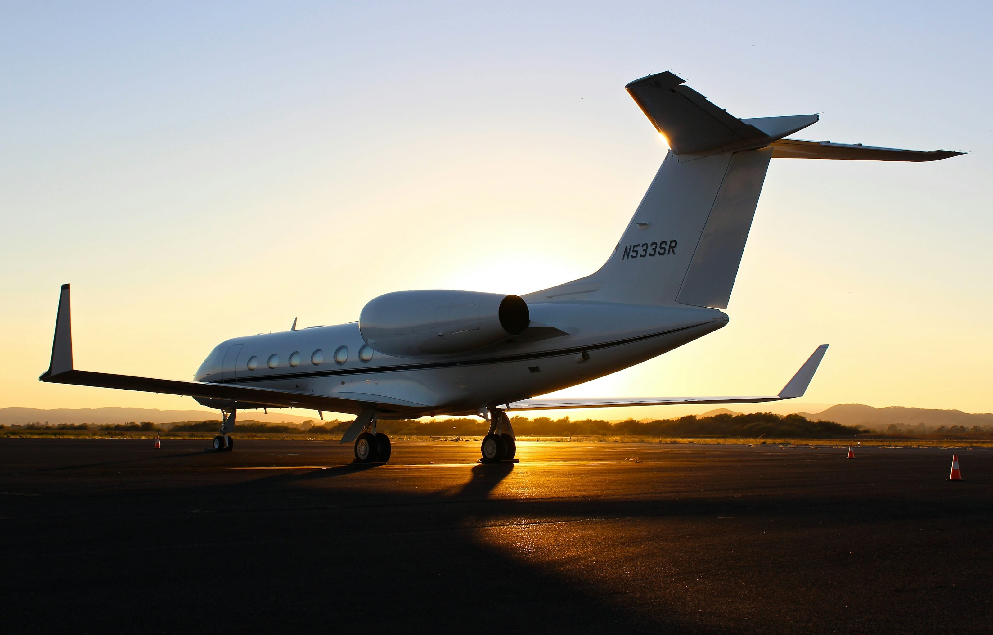 Jet ejecutivo estacionado en plataforma al atardecer