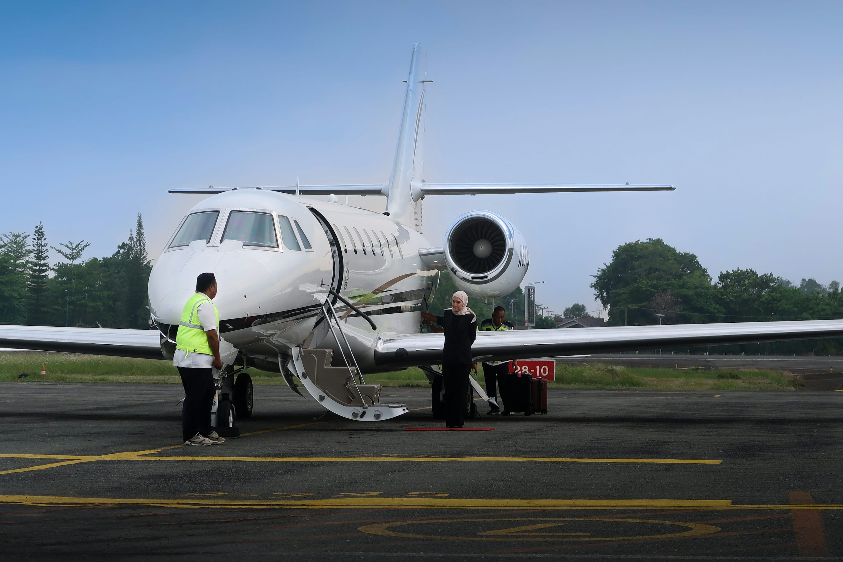 Personal de tierra junto a un jet ejecutivo con la escalera desplegada